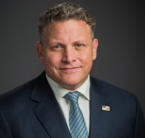Robert Head Shot with Brown Background Blue Suit